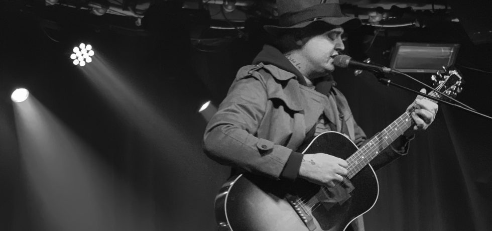 Black and white image of Pete Doherty playing guitar