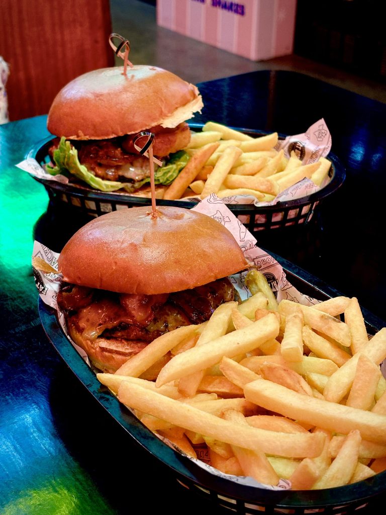 Two burgers with chips in baskets on a dark table at Fat Bob's Moorabbin