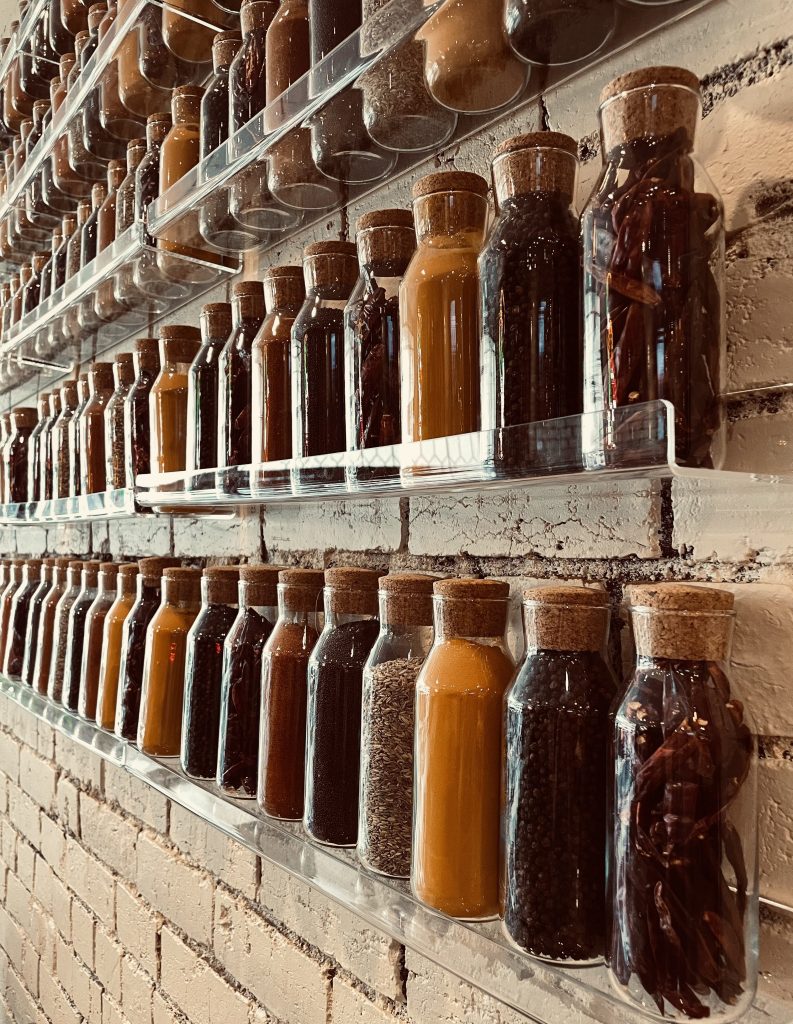 Wall of large spice bottles with different coloured spices - Hop and Spice, Ascot Vale