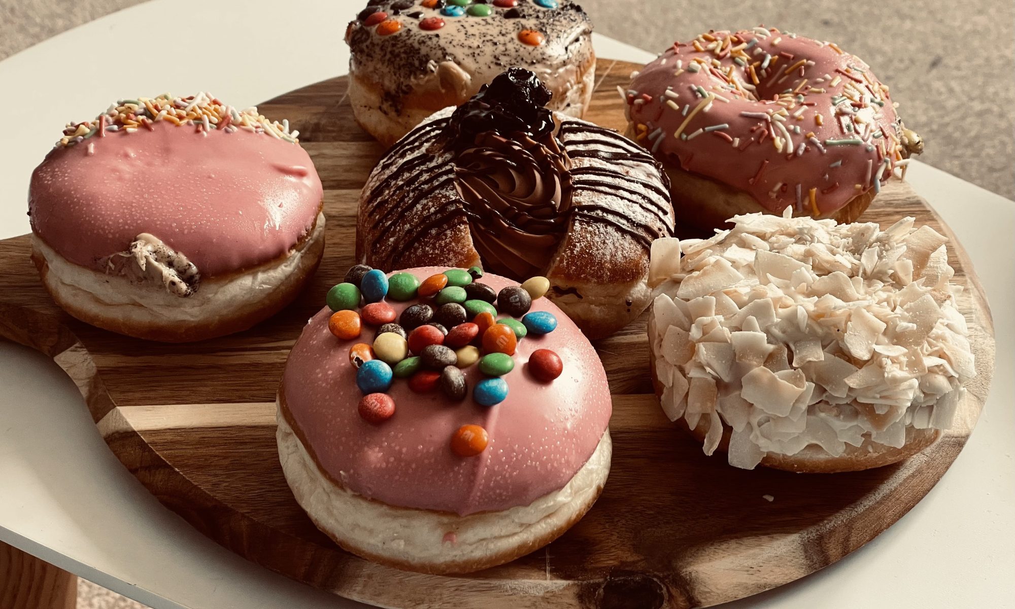 Round board with six Daniel's donuts on a white table