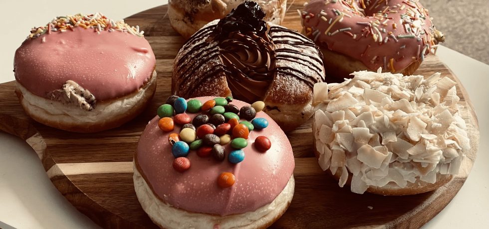 Round board with six Daniel's donuts on a white table