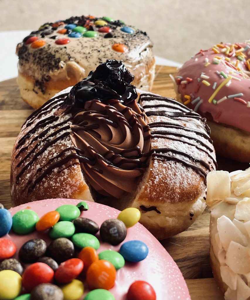 Close up of several Daniel's donuts with New Zealand style chocolate filled donut in the middle
