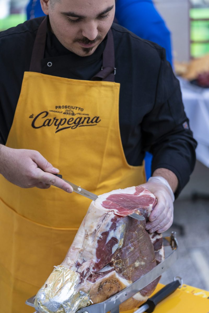 Man hand checking Carpegna meat in yellow apron