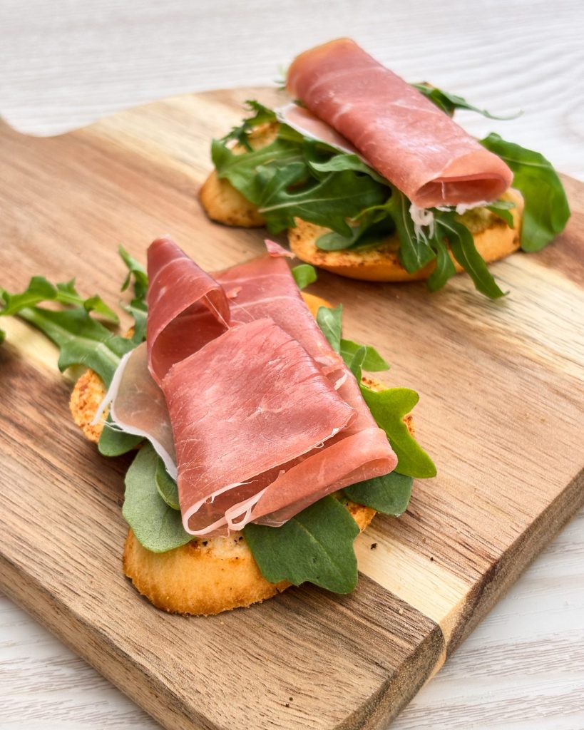 Prosciutto crostini on wooden platter