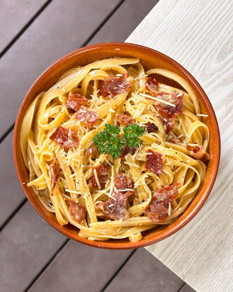 Flatlay of carbonara in brown bowl. 