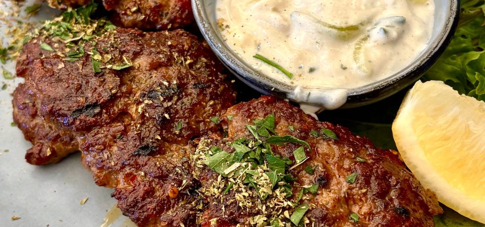 Bifteki with small bowl of Tzatziki on grey plate from St. James Souvlaki Bentleigh