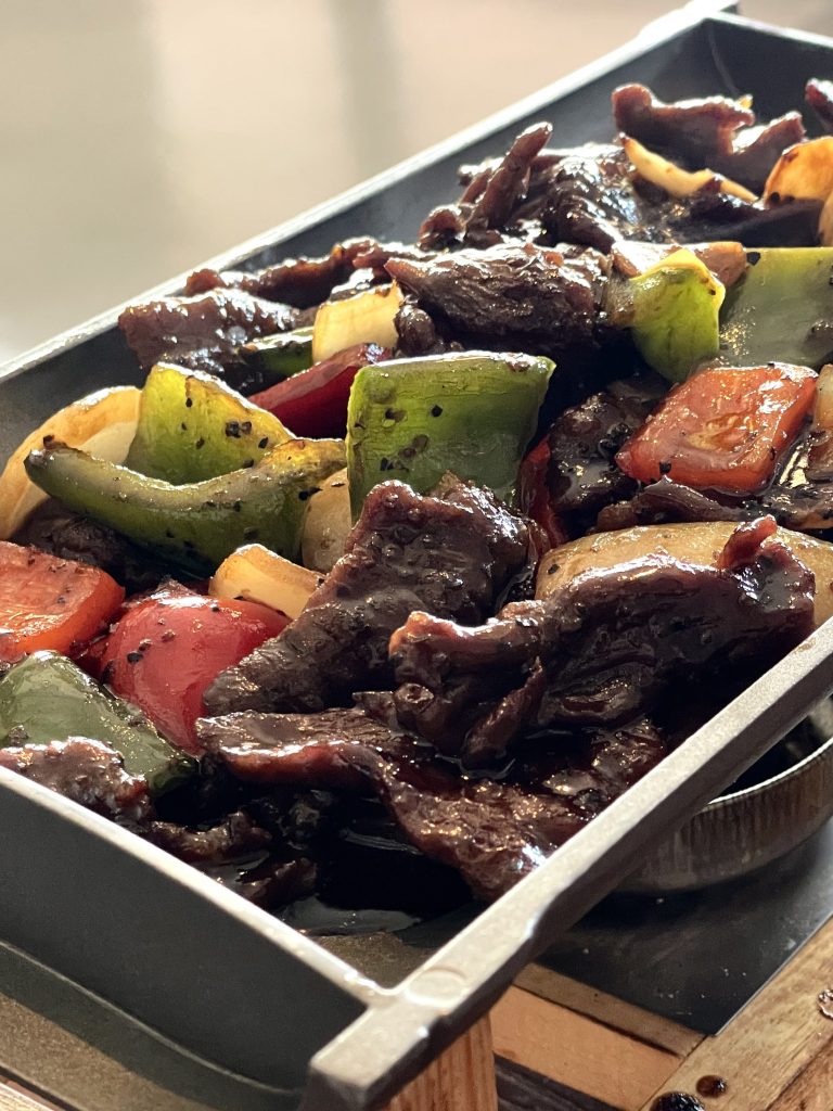 Beef in black pepper sauce on wooden tray from Jymmanuel Eatery Ripponlea