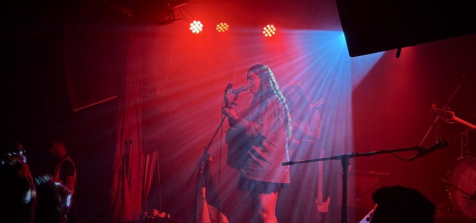 Mia Wray playing guitar and backlit by red light at the corner hotel melbourne