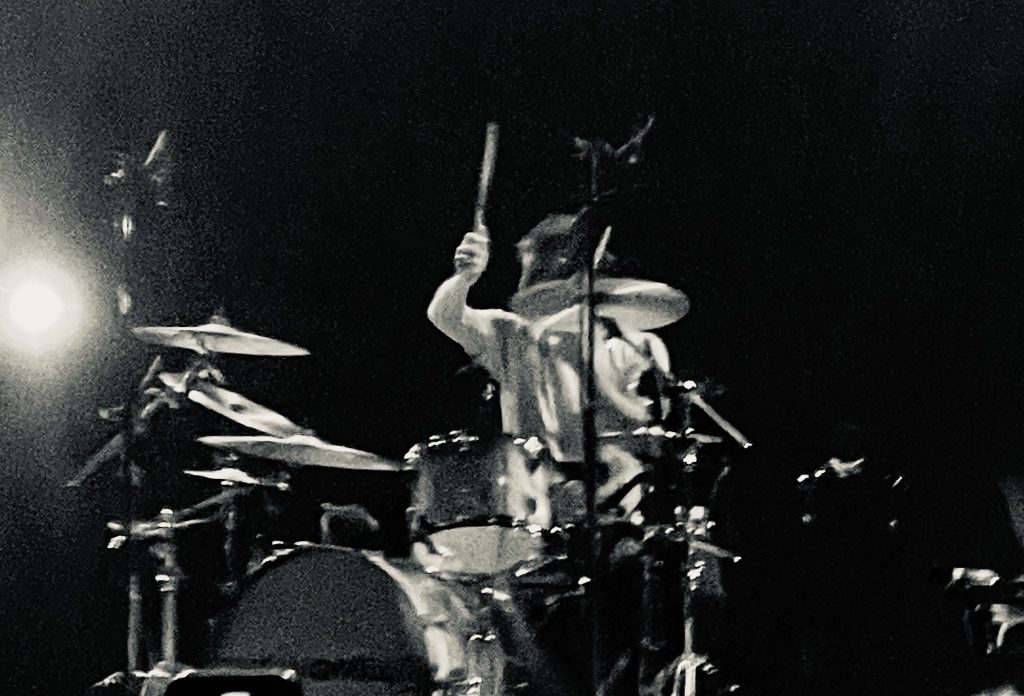 Dan of the Wombats hitting those drums at their gig at Festival Hall, Melbourne. Image is black and white.