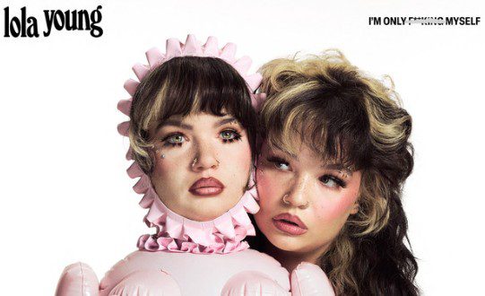 Lola Young with a doll of herself against a white background. Cover art for I'm only f**king myself
