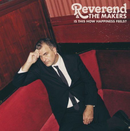 Jon McClure of Reverend and The Makers on a red sofa. Cover image for Is This Happiness