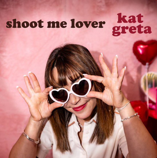 Kate Greta wearing heart shaped sunglasses against a pink background. Shoot me lover single cover