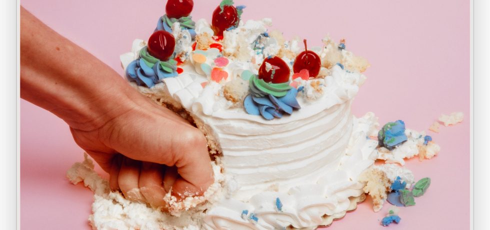 A hand punching a white cake on a pink background - The Buoys Bitch single cover
