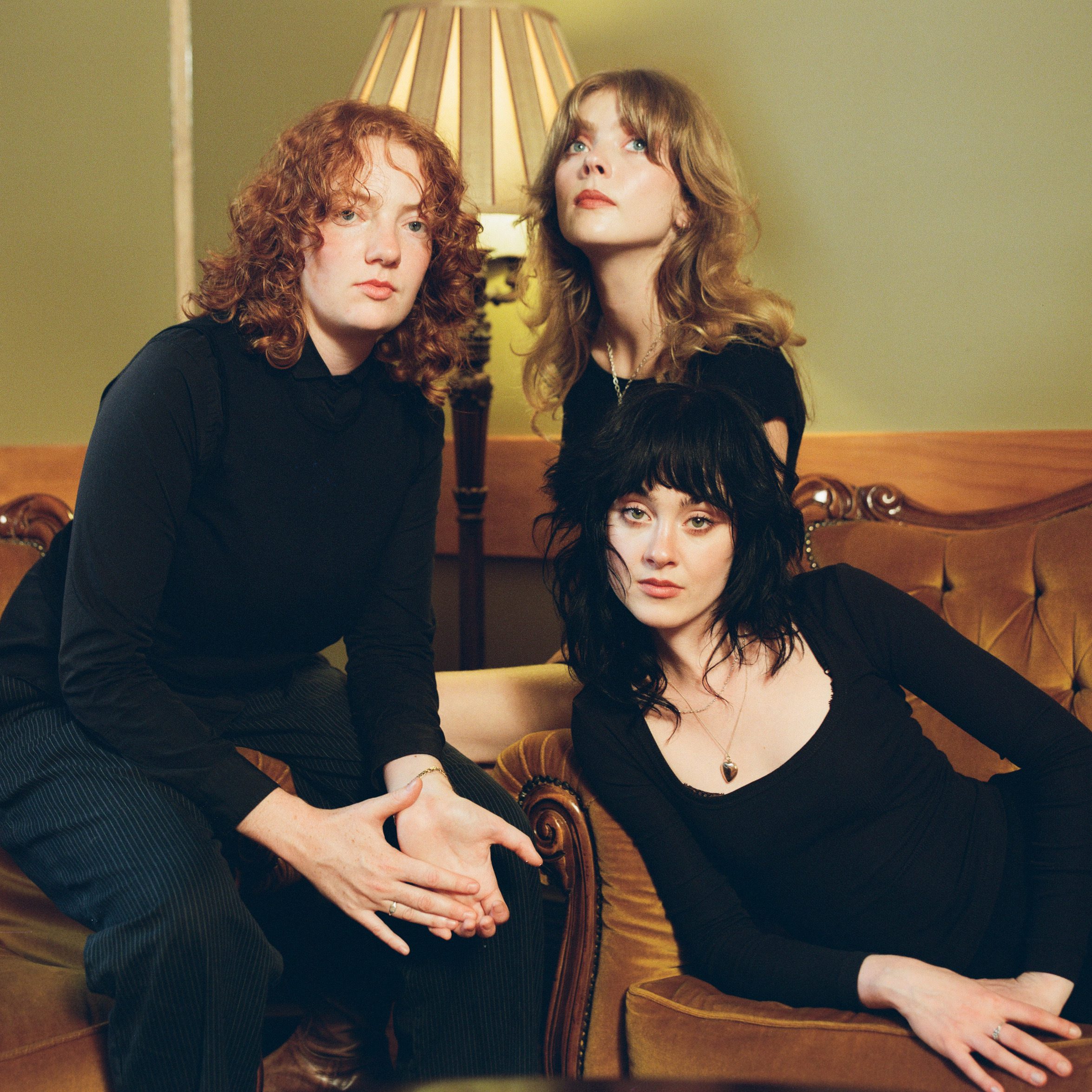 Band Folk Bitch Trio dressed in black sat on sofas