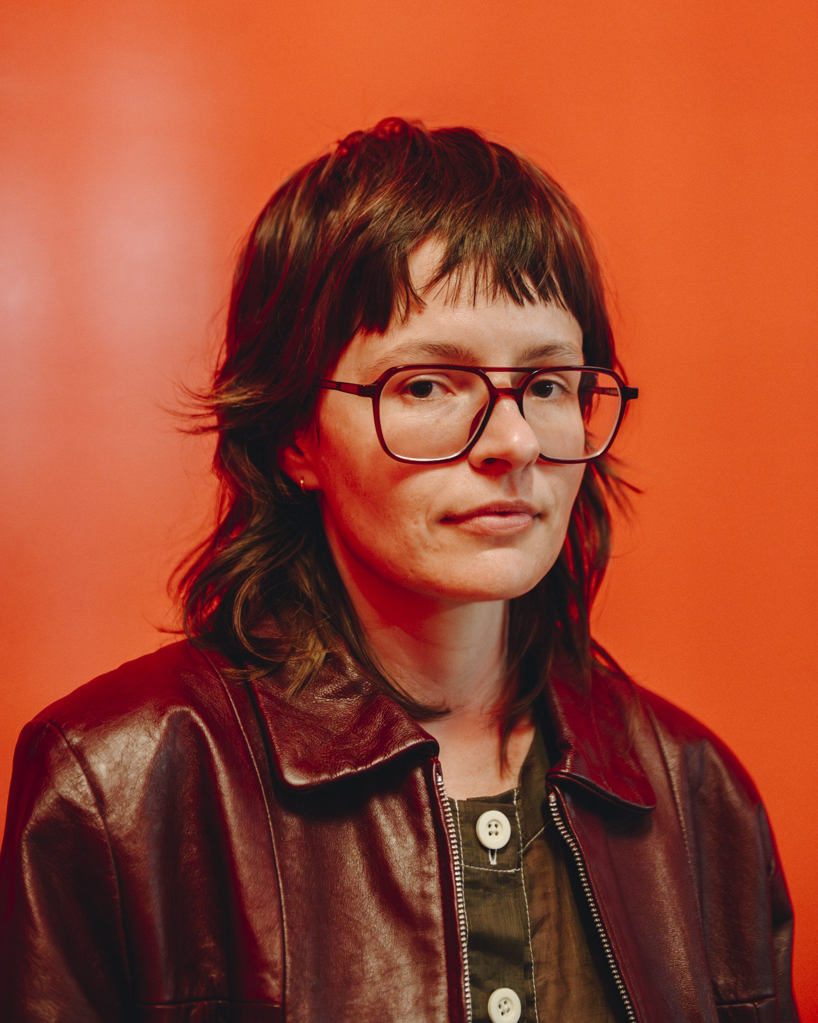 Singer Ruby Gill in a brown jacket in front of an orange wall