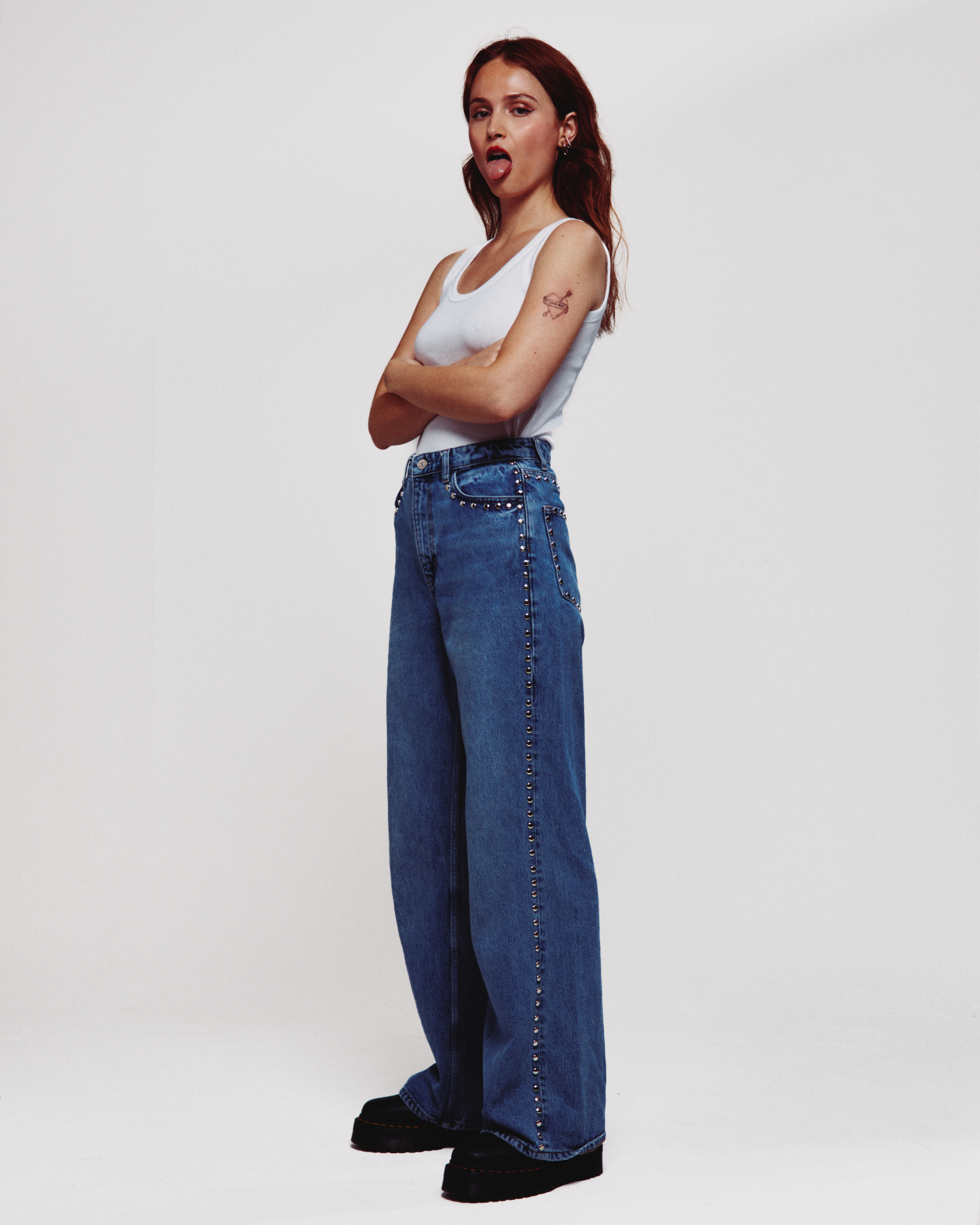Image of singer Sofia Gobbi in jeans and a white singlet sticking her tongue out. Press image for Bigger Man 