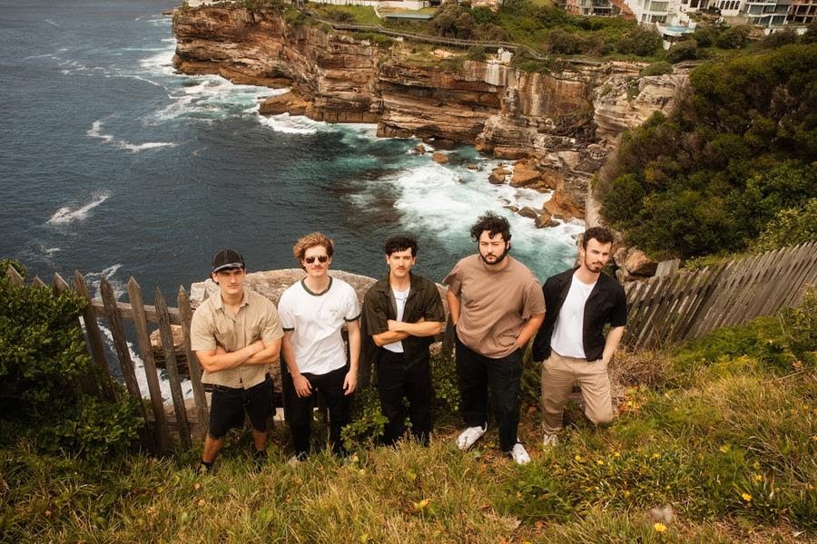 The Sooks stood on a cliff top with the sea in the background. Press image for take it slow