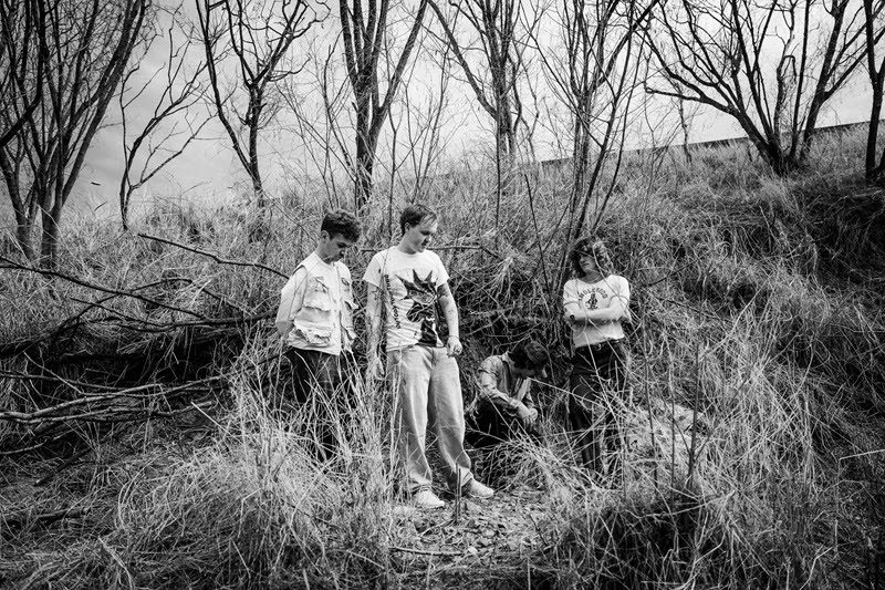 Black and white image of band Vinted Vineer in a bush location with tall grass and trees 