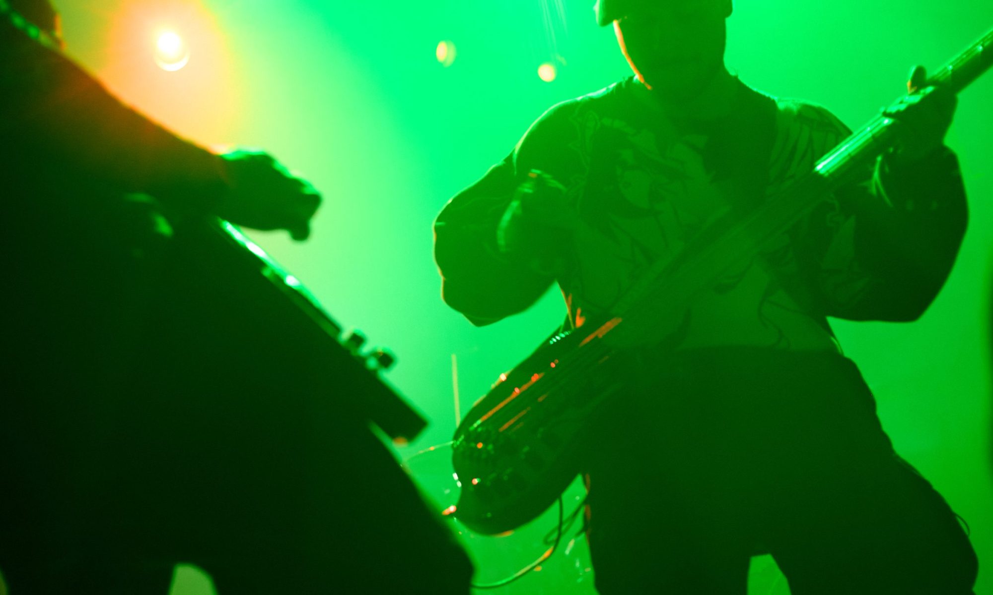 Blurred guitarist silhouette against green light