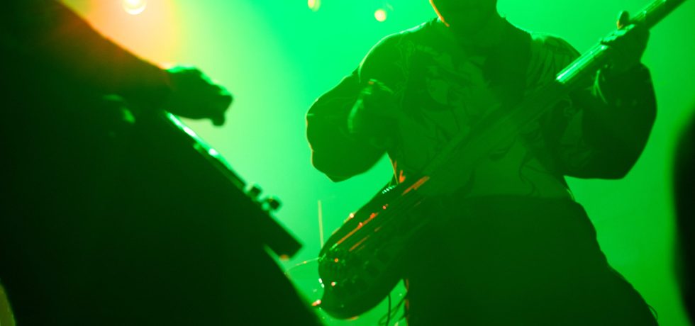 Blurred guitarist silhouette against green light