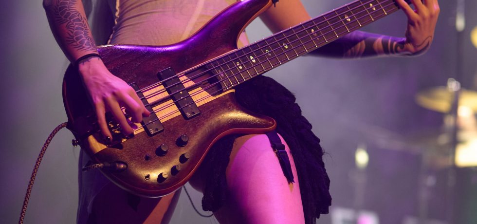 Close up of bass guitar player under purple lighting.