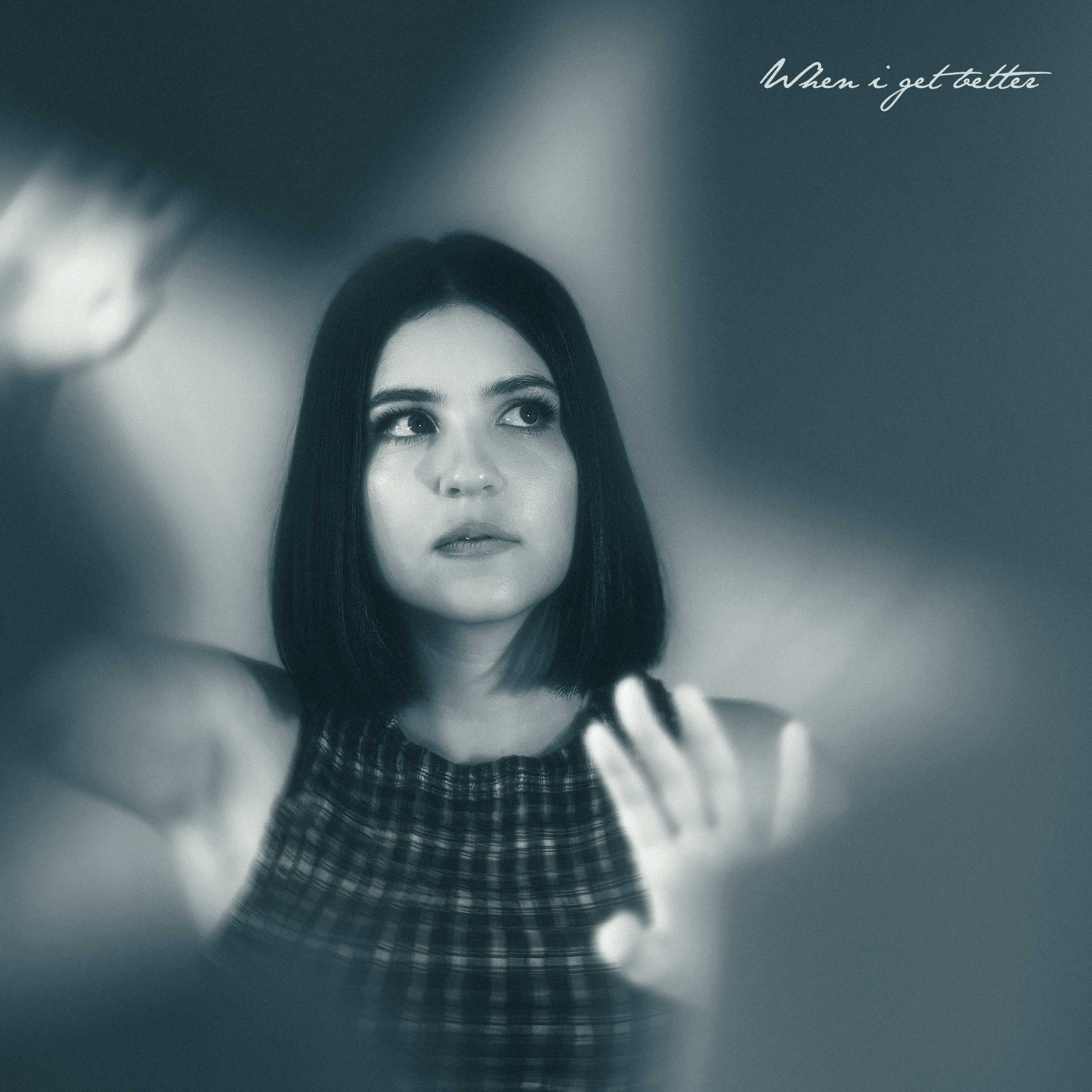 Black and white image of Amber Farnan with her hands up to the lens. Single cover for When I get better