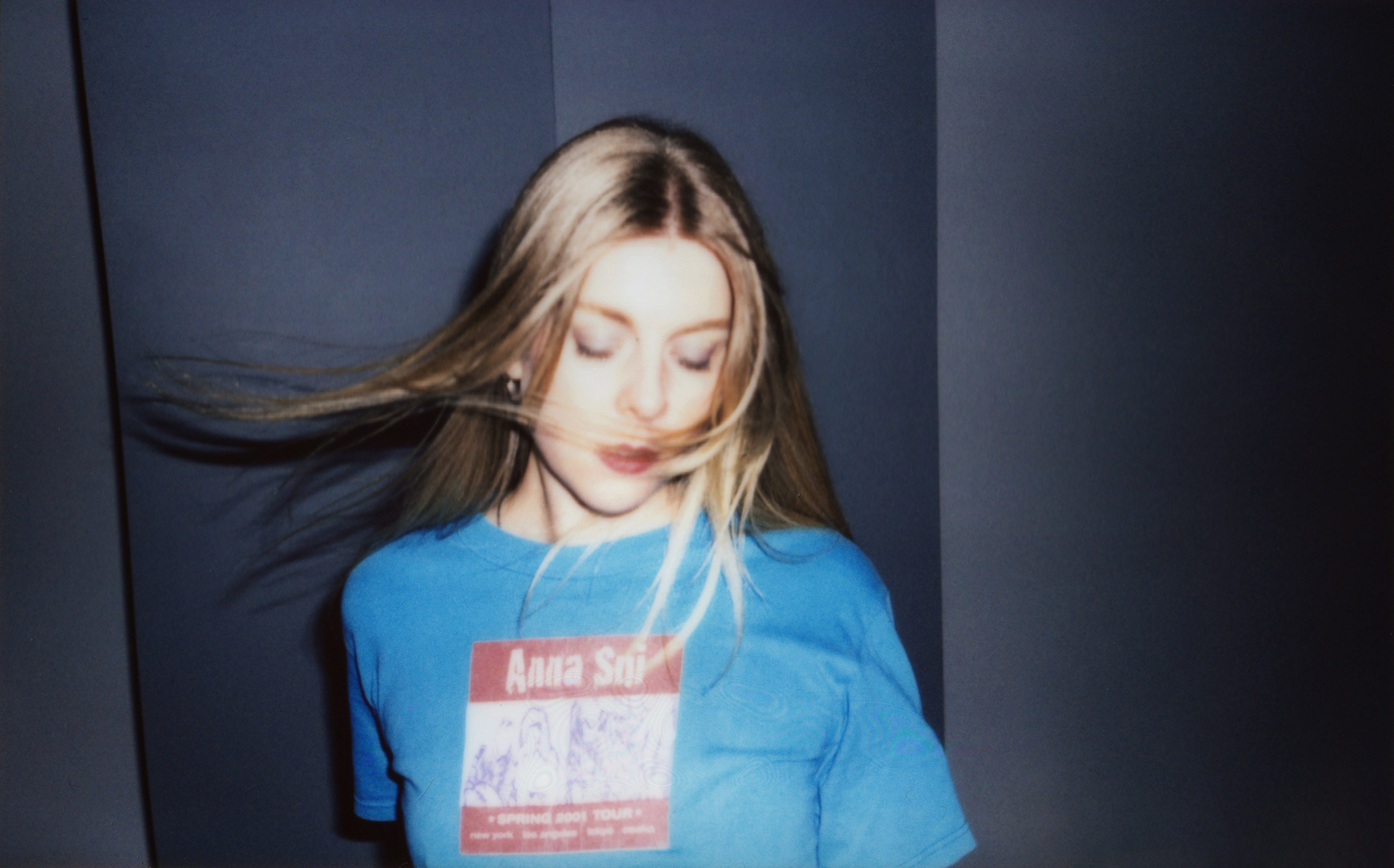 Image of Juice Webster in a blue sweater swishing her hair